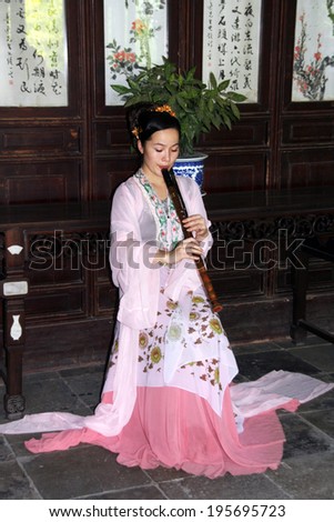 Suzhou, China - July 20, 2007: Young woman plays flute at a free show for tourists in a garden in Suzhou on July 20, 2007. Flute is one of traditional chinese musical instruments.