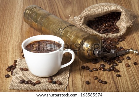 Coffee beans, white cup with a coffee drink and coffee grinder