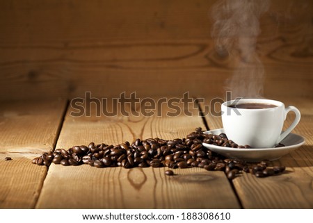 White coffee cup and coffee beans on old wooden background.