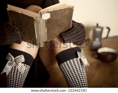 A cup of coffee or hot chocolate and female with book and sweet brown socks on a wooden background.