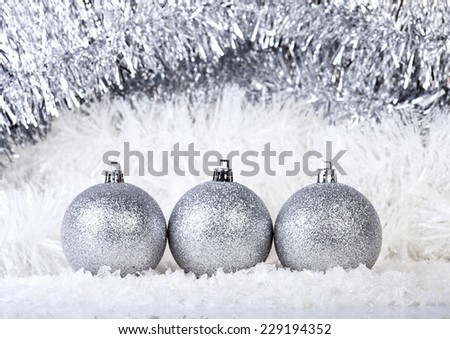 Silver Christmas balls on a snow and garlands background.