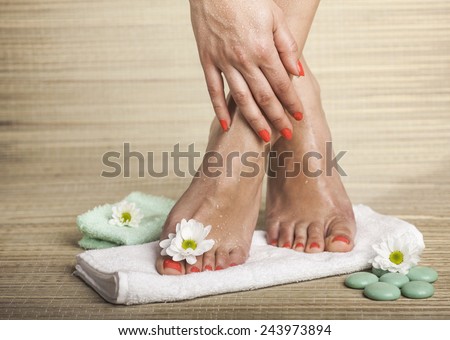 Female feet and hand with drops of water, towel, flowers and spa rocks. Copy space.
