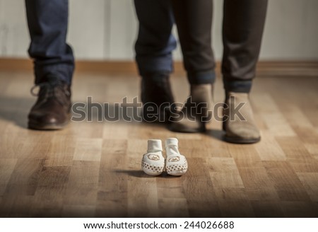 Parents waiting for a baby. Mother and father with elegant shoes and baby shoes in front of them.