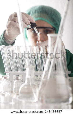 Closeup of a female scientist filling test tubes with pipette in laboratory.