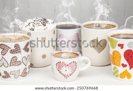 Lots of coffee in different cups with hearts and smoke.