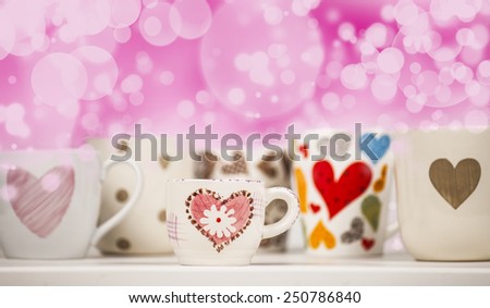 Lots of coffee in different cups with hearts and beautiful pink bokeh.