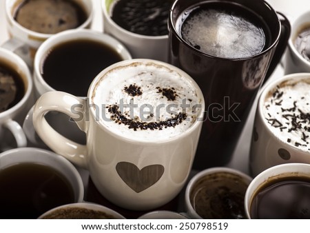 Lots of coffee in different cups with hearts and smile in one of them.
