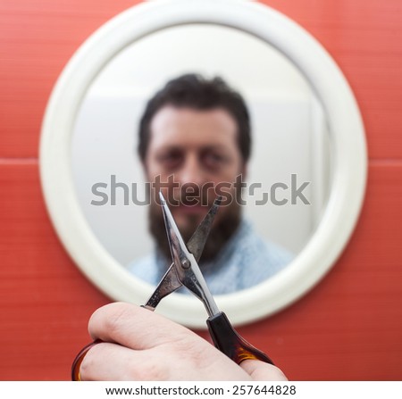 Bearded man preparing to cut his beard with scissors