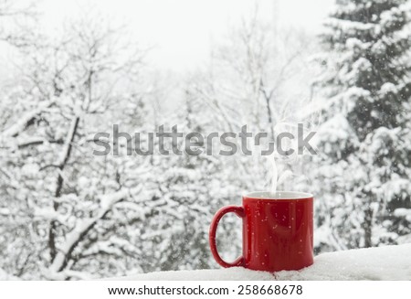 Red cup of coffee on a beautiful snow winter background.