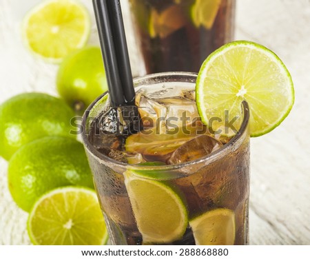 Cuba Libre Cocktail with lime on a white wooden background