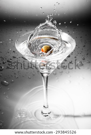 Glass of martini cocktail with olives and splashes