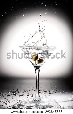 Glass of martini cocktail with olives and splashes