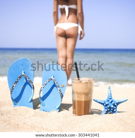 Iced coffee, blue flip-flops, starfish and beautiful woman on a sandy beach
