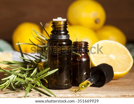Lemon essential oil, lemon fruit and rosemary on wooden background