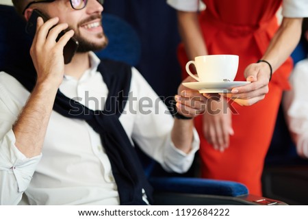 Close up of unrecognizable flight attendant serving cup of coffee to handsome man sitting in first class and enjoying flight, copy space