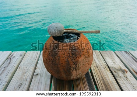 water jar on wooden floor with sea background