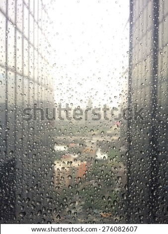 Rain drops on window surface with soft focus city view