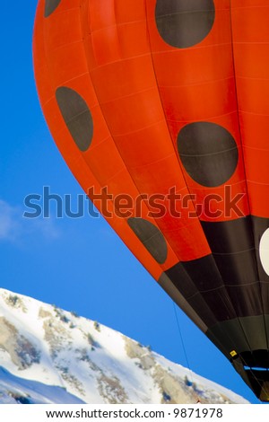 black points on a red hot air balloon in the swiss alps