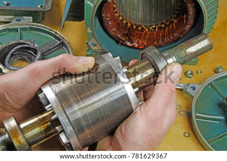 Three phase induction   motor bearing repair – A fitter/technician  checking motor windings resistance readings with a multi meter and  checking for faults on shaft bearings, .
