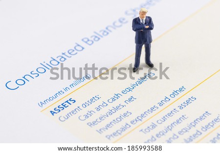 miniature businessman stand on the balance sheet