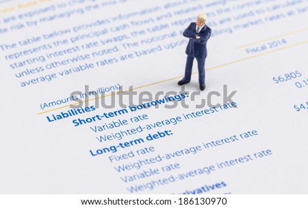 miniature businessman stand on the balance sheet