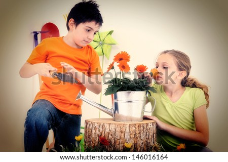Attractive Caucasian boy and girl with flowers, tools, garden supplies.  Studio Portrait.