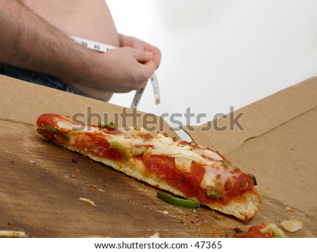 Close up of a slice of pizza in a box with man measuring his belly in the background.