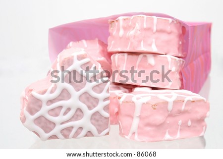 Pink and white iced heart shaped cakes in a pink bakery bag.
