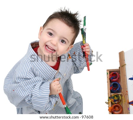 Small boy in dad's shirt painting at a wooden easel.