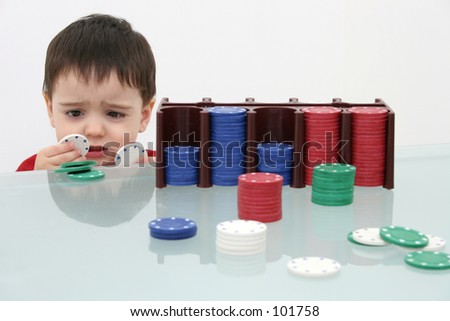 Small boy behind a stack of poker chips.