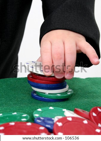 Poker chips on a green felt top table being stacked by a child\'s hand.