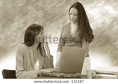Two beautiful young women working together with laptops at a restaurant table.