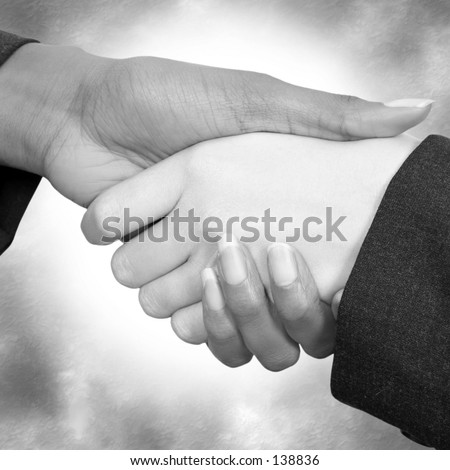 Two woman shaking hands.  Business suit sleeves.