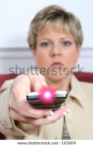 Woman aiming tv remote towards camera.  Also available wiht light off.