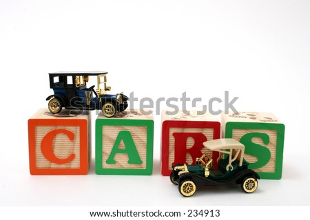 Antique black cars on ABC blocks spelling cars. Shot on white background.