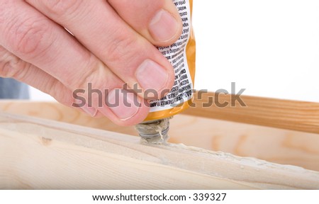 Close Up Rough Hand Squeezing Wood Glue on Cabinet.