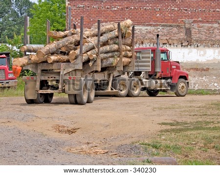 Logging truck in dirt parking lot.