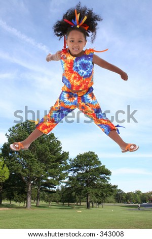 Six year old girl in colorful summer outfit at the park jumping.