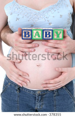 Alphabet Blocks Held By Expecting Parents Over Mom\'s Belly.