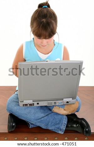 Beautiful Little Girl Working On Laptop Computer. Sitting crossed leg on a table.  Shot in studio over white.