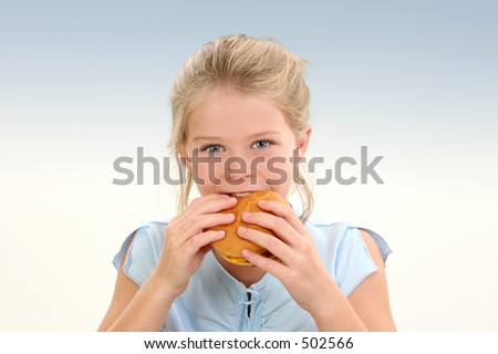 Beautiful Little Girl Eating a Cheeseburger over blue background.  Shot in studio.