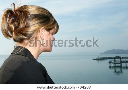 Young woman taking a break out by the lake.  Casual business attiire.  Looking out at water.