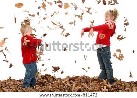 Happy two year old boy and five year old sister throwing leaves at each other.