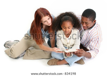 Family of three reading child\'s bible together.  Caucasian mother and African American Father with daughter.