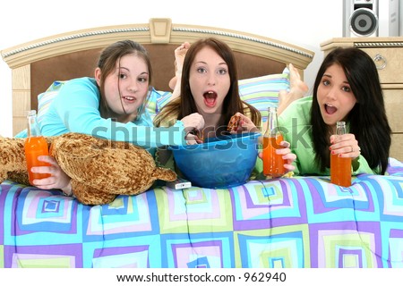 Three teen girls eating and watching television at home.