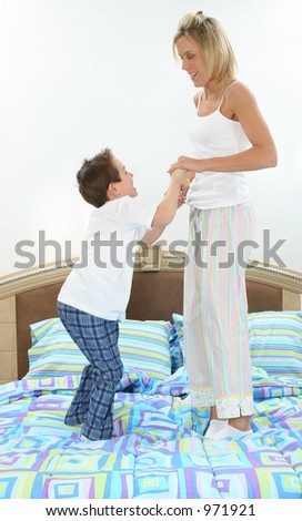 Mom and son in pajamas playing in bed.