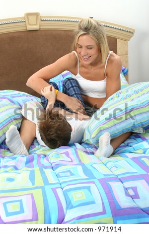 Mother and son having tickle fight in bed.