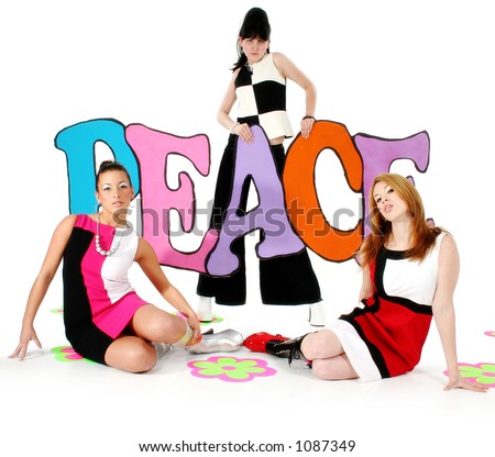 Three beautiful young woman in go-go boots and mini dresses holding colorful peace sign.  60\'s theme. Shot in studio over white.