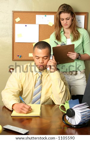 Handsome African American business man and his secretary taking notes.