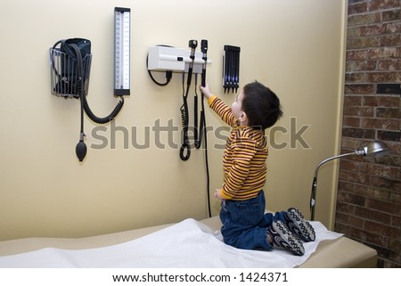 Small boy playing with exam equipment while the doctor is out.